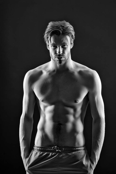 Man with six pack and ab muscles. Athlete with fit body in shorts. Sportsman with sexy torso and chest. Training and workout activity in gym. Sport or fitness and bodycare concept, black and white. - Foto, Imagem
