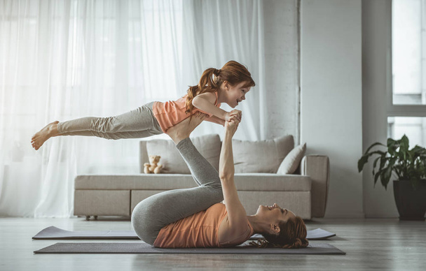 Daughter is enjoying fitness with mommy at home - Foto, Bild
