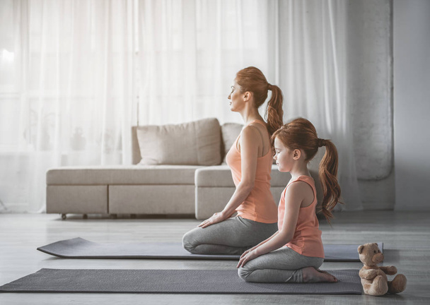 Woman and her child are meditating at home - Photo, image