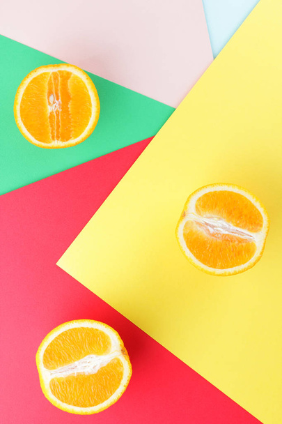Fruits of oranges on a multicolored background, halves of oranges on colored paper. Copy space. Citrus in the style of pop art - Фото, изображение