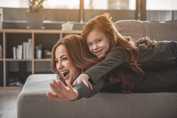 Cute child and pleased mom amusing themselves at home - Photo, image