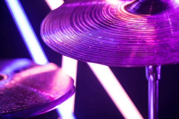 Барабанные тарелки крупным планом, с барабанными палочками на фоне цветных фонарей. Капли воды на тарелки
. - Фото, изображение
