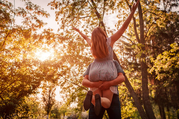 Счастливая влюбленная пара веселится в цветущем саду. Мужчина держит свою девушку в руках и крутится на закате. Парни наслаждаются жизнью
 - Фото, изображение