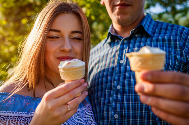 アイスクリームを食べると外チャット幸せな若いカップル。女と男でなごむ春夕暮れ時の庭。ライフ スタイル - 写真・画像