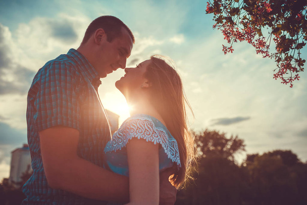 Happy couple in love hugging and smiling in spring park at sunset. Romantic date - Photo, Image