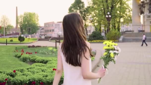 Young pretty woman holding a bouquet of beautiful flowers. Female hand touching beautiful flowers. Enjoying nature - Felvétel, videó