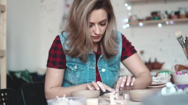 çekici genç beyaz bir kadın yaratıcı hobi arkasında zaman harcıyor. Kız, heyecanla bir tabak kil atölye sculpts - Video, Çekim
