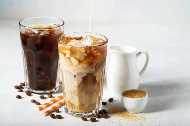 Café helado en un vaso alto con crema y granos de café. Bebida fría de verano sobre un fondo azul claro
. - Foto, imagen