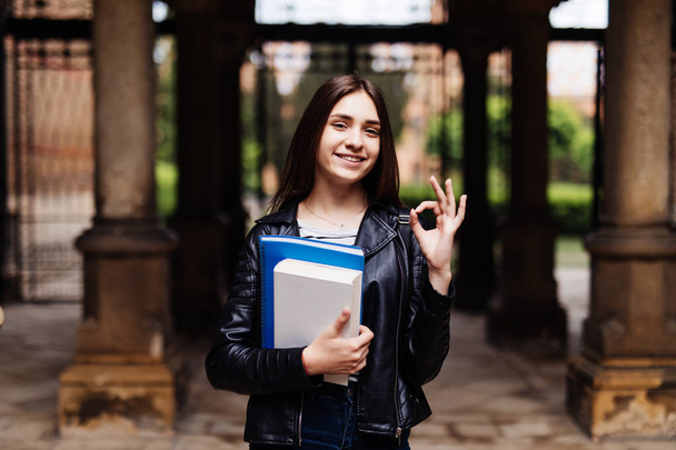 Portrait of a smiling female student showing thumb up outdoors - Photo, Image