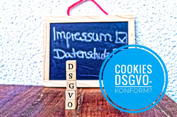 Building blocks with the inscription DSGVO (Datenschutzgrundverordnung) in English GDPR (General Data Protection Regulation) and a board with the inprint and Privacy Policy and Cookies DSGVO-compliant (in german Cookies DSGVO-konform
) - Фото, изображение