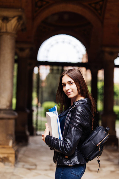 Счастливая молодая женщина студентка с рюкзаком держа книги и ходить на открытом воздухе
 - Фото, изображение