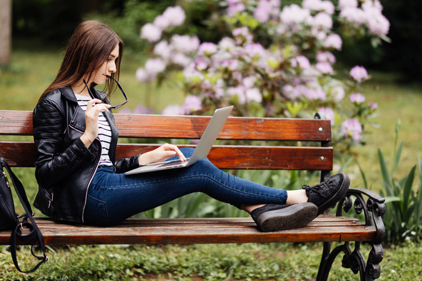 Girl using a laptop on a bench - Foto, afbeelding
