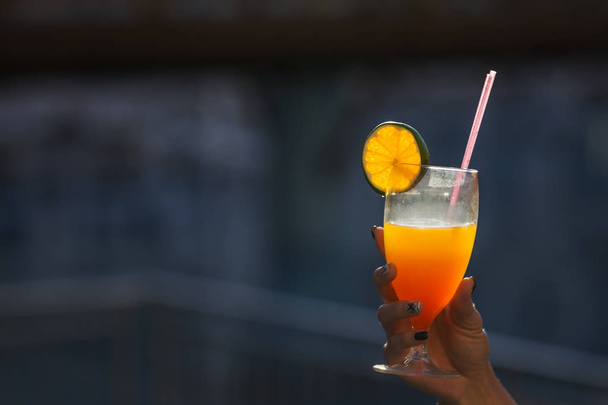hand holding a cocktail with an orange in glass outdoor - Foto, Imagem
