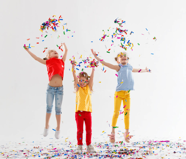 szczęśliwe dzieci na wakacje miłej zabawy i skoki w kolorowe konfetti na białym tle - Zdjęcie, obraz
