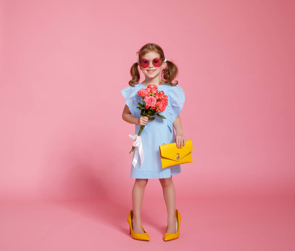 funny child girl fashionista in big mother's yellow shoes on colored background - Fotó, kép