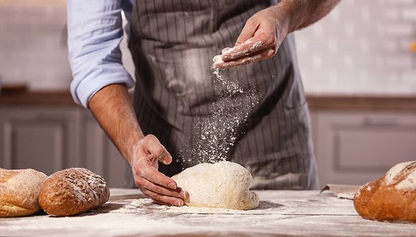 hands of the baker's male knead dough - Фото, изображение