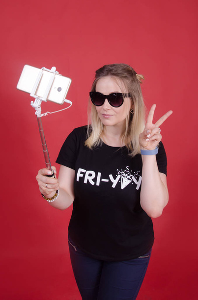 Woman making selfie with smartphone. Woman selfie with mobile phone on monopod wearing sunglasses. Summer and youth, hipster concept - Фото, изображение