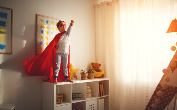 niña con un disfraz de superhéroe con máscara y capa roja en hom
 - Foto, imagen
