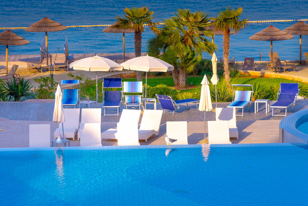 Belle piscine extérieure de luxe avec parasols et chaises longues
 - Photo, image