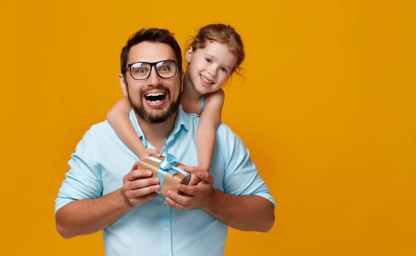happy father's day! cute dad and daughter hugging on colored yellow backgroun - Fotoğraf, Görsel