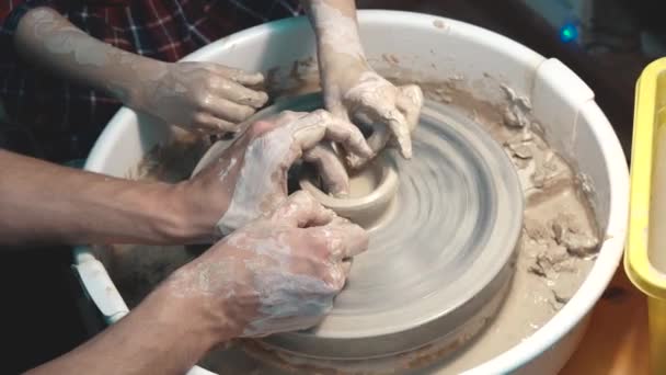 Potter potters tekerlek üzerinde çalışmak için çocuk öğretir. Yetişkin ve çocuk elleri yakın çekim. - Video, Çekim