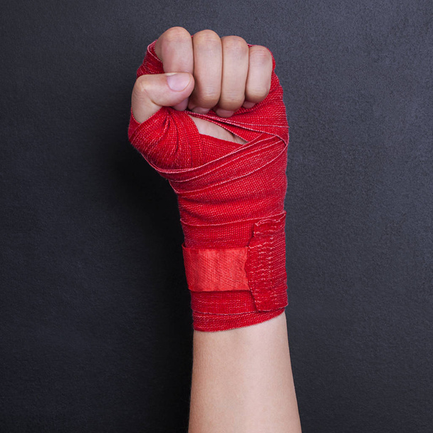 Female hand in a bandage with red boxing tape is raised upwards as a symbol of the struggle for rights. Fight like a girl - Photo, image