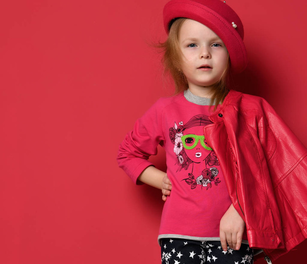 Five years old baby girl child kid posing in red leather jacket and hat  on red - Фото, зображення