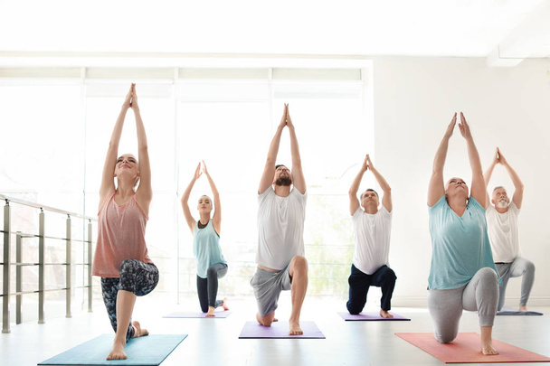 Group of people in sportswear practicing yoga indoors - Foto, afbeelding