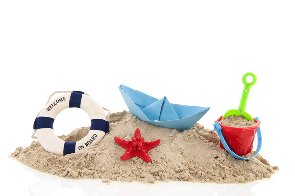 Praia com bóia de vida e brinquedos na areia isolados sobre fundo branco
 - Foto, Imagem