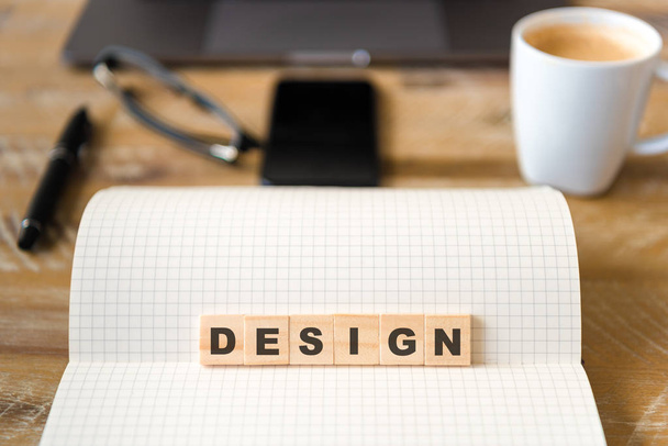 Közelkép a notebook felső fa asztal háttere, így Design szó betű fadarabot összpontosítani. Üzleti koncepció kép. Laptop, szemüveg, toll és mozgatható telefon-ban defocused háttér - Fotó, kép