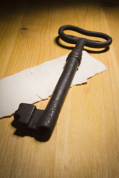 Old rusty key on a wooden table - Фото, изображение