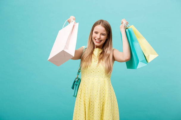 Portrét mladé šťastná usmívající se žena s nákupní tašky. Modré pozadí. - Fotografie, Obrázek