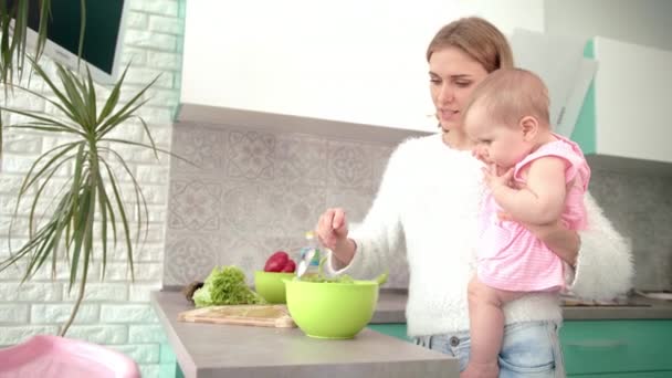 Moeder houdt baby 's vast in de keuken. Moeder met kind bereiden diner - Video