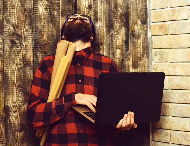 Bearded brutal caucasian hipster holding laptop and craft paper - Foto, afbeelding