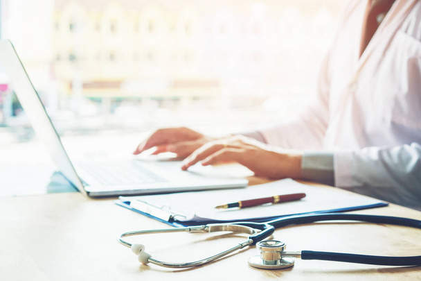 Arzt tippt Informationen auf Laptop im Krankenhaus Büro Fokus auf Stethoskop - Foto, Bild