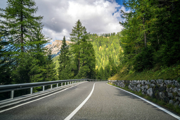 Hermoso camino de montaña con árboles, bosques y montañas en los fondos. Tomado en la carretera estatal de la montaña Dolomitas en Italia
. - Foto, Imagen