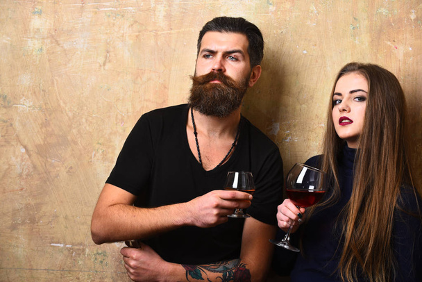 Girlfriend and boyfriend with curious faces drink wine and cognac - Fotó, kép