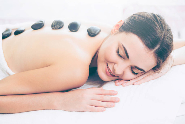 Woman getting hot stone massage treatment by professional beautician therapist in spa salon. Luxury wellness, back stress relief and rejuvenation concept. - Foto, Imagen