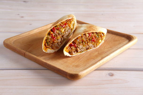 Burritos wraps with meat, beans and vegetables on wood board - Fotoğraf, Görsel