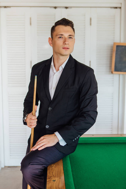 Young handsome man dressed in classic costume playing billiard game alone - Фото, зображення