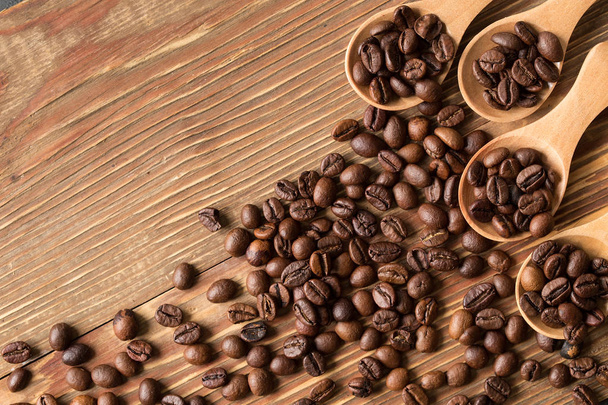Coffee beans in a wooden spoon on rustic  background. Food ingredients, top view, space for text - Фото, зображення