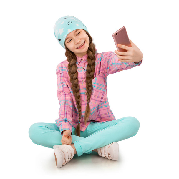 Lachende meisje houden van mobiele telefoon en het maken van de selfie geïsoleerd op witte achtergrond - Foto, afbeelding