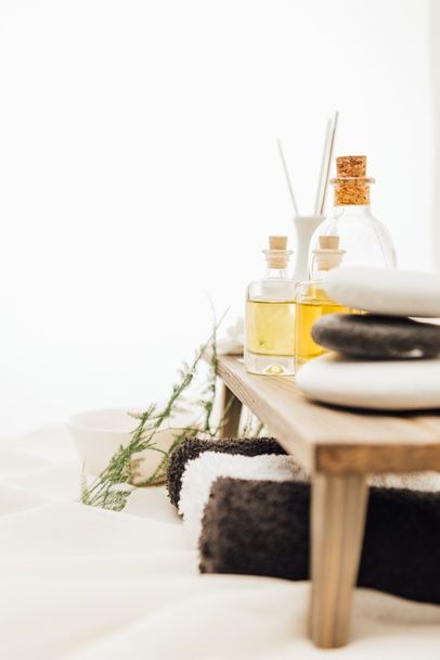 vue rapprochée de la disposition des accessoires de traitement spa avec fougère, serviettes, huile et sel sur fond blanc
 - Photo, image