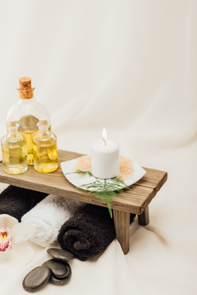 close up view of arrangement of spa treatment accessories with essential oil, salt and candle on white background - Фото, изображение