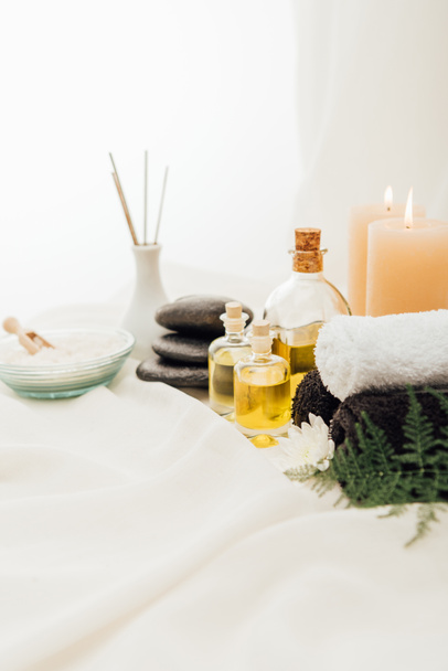 close up view of arrangement of spa treatment accessories with candles and pebbles on white background - Fotoğraf, Görsel