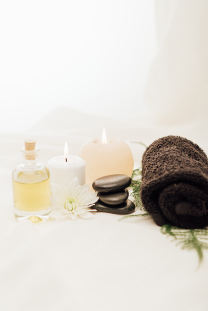 close up view of arrangement of spa treatment accessories with candles and pebbles on white background - Photo, Image