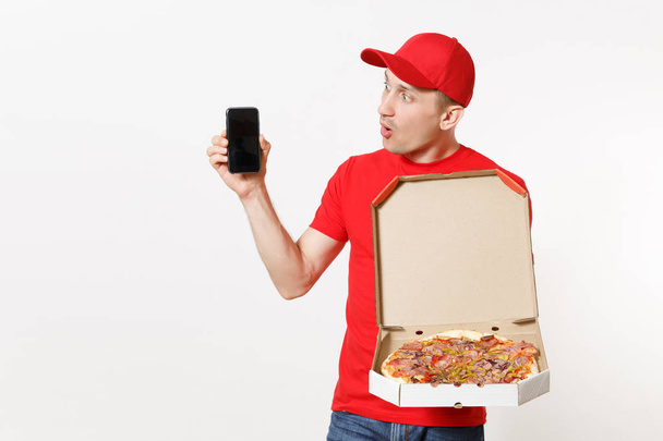 配信は、白い背景で隔離赤い制服を着た男の笑みを浮かべてします。男性 pizzaman キャップ、t シャツ持株携帯画面空、段ボール flatbox のイタリアのピザ宅配便。コピー スペース - 写真・画像