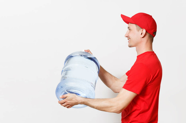 Content delivery courier or dealer man in red uniform carrying bottle of fresh water to office cooler isolated on white background. Professional happy male in cap shirt. Copy space for advertisement - Photo, image
