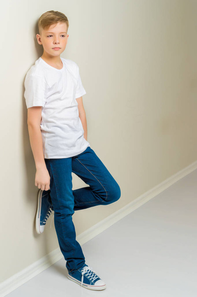A fashionable school-age boy leaned against the wall. - Foto, Imagen