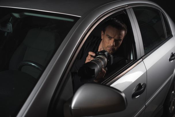 male paparazzi doing surveillance by camera with object glass from his car  - Foto, imagen